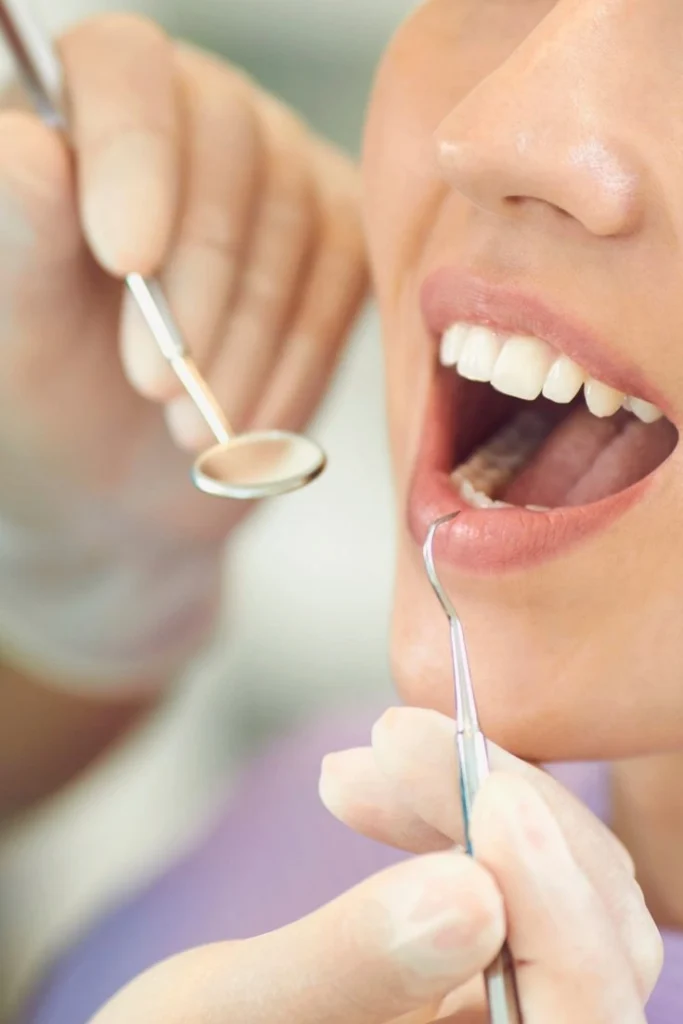 Dentist using a mirror and probe to check a patient's teeth during a cosmetic dentistry treatment in Glendale, AZ